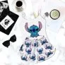 Conjunto de pijama feminino com estampa do Stitch exibido sobre superfície branca ao lado de café, óculos escuros e revistas